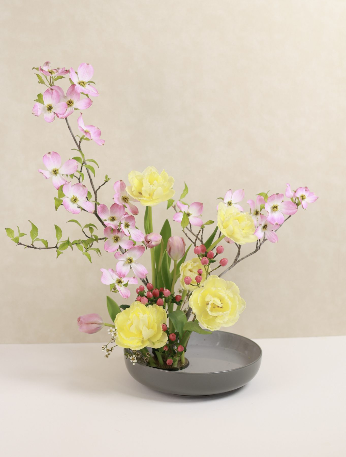 An ikebana-style arrangement of dogwood, tulips, and berries.