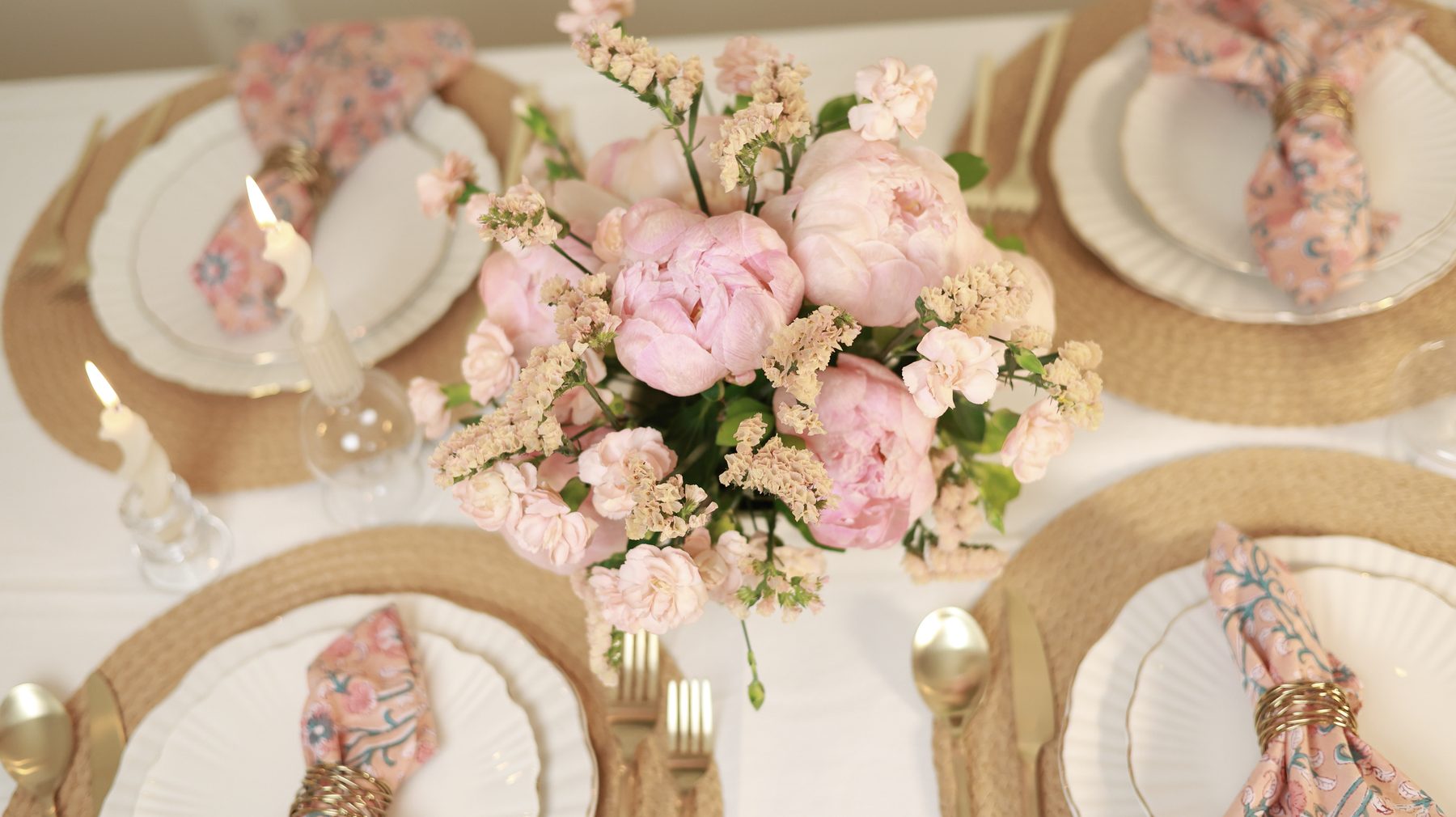 A peach peony centerpiece styled on a table set for four.